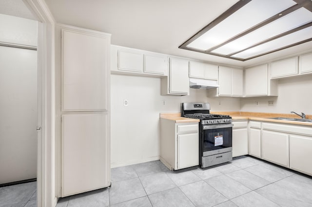 kitchen featuring sink, gas stove, white cabinets, and light tile patterned flooring