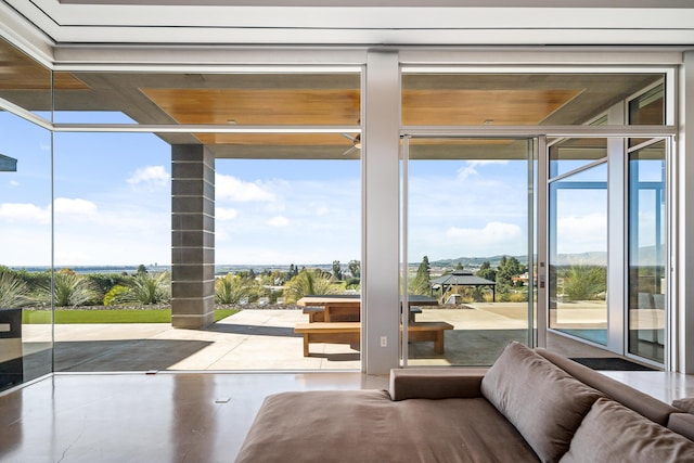 doorway with concrete floors, plenty of natural light, and floor to ceiling windows