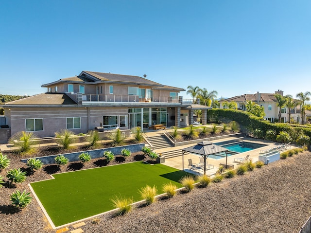 rear view of house featuring a yard, a balcony, and a patio