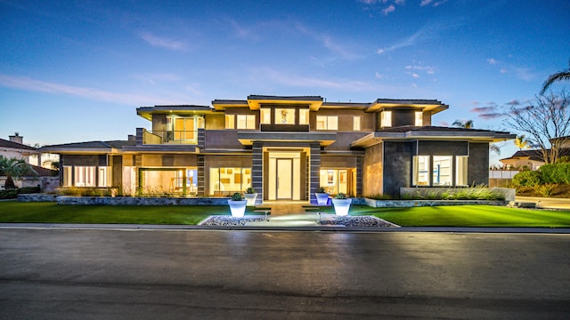 prairie-style home featuring a balcony and a front yard