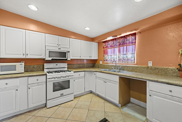 kitchen featuring white appliances, white cabinets, a sink, and light tile patterned floors