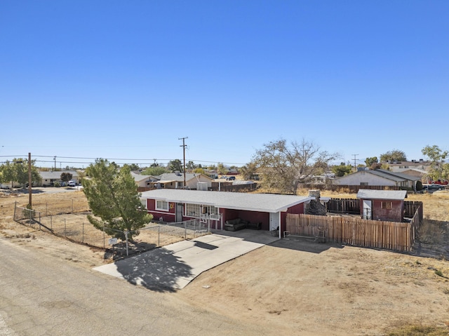 view of front of property with concrete driveway, an attached carport, and fence