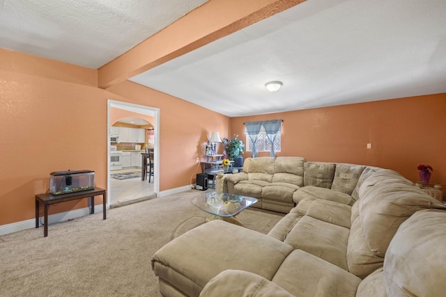 living room with carpet, beam ceiling, arched walkways, and baseboards