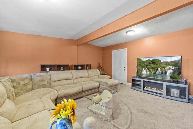 carpeted living area featuring a textured ceiling, beam ceiling, and a glass covered fireplace