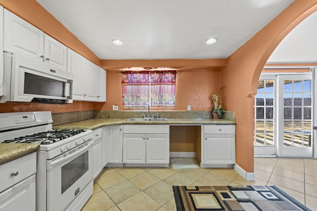 kitchen with white appliances, white cabinets, light countertops, a sink, and light tile patterned flooring