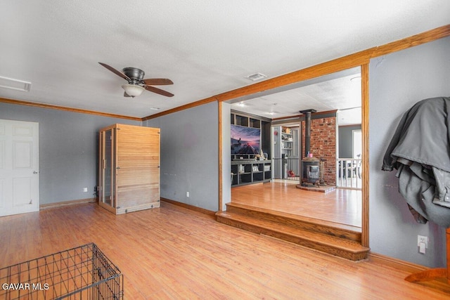 809 Berncastle Rd, Acton, CA 93510 - empty room with a wood stove, wood finished floors, ornamental molding, and a ceiling fan