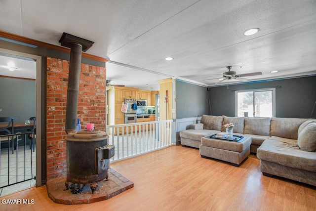 809 Berncastle Rd, Acton, CA 93510 - living room featuring ceiling fan, a wood stove, crown molding, light wood-type flooring, and a textured ceiling