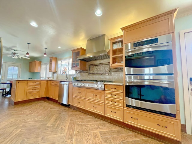 kitchen featuring wall chimney range hood, hanging light fixtures, crown molding, light brown cabinetry, and stainless steel appliances