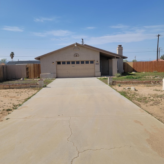 view of front facade featuring stucco siding, driveway, fence, and a garage