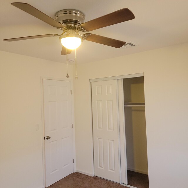unfurnished bedroom featuring dark colored carpet, baseboards, visible vents, a closet, and ceiling fan
