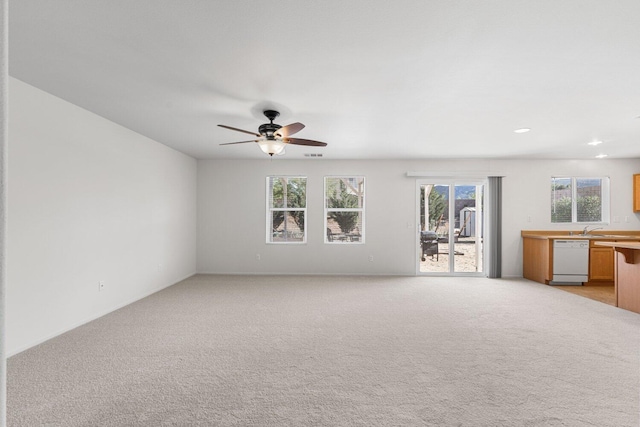7150 Lyric Ave, Lancaster, CA 93536 - unfurnished living room featuring ceiling fan, plenty of natural light, light carpet, and a sink