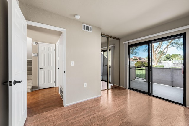 spare room with wood finished floors, baseboards, and visible vents