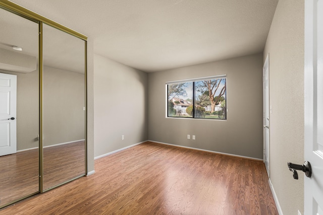 unfurnished bedroom with a closet, baseboards, and wood finished floors