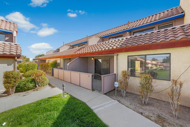 exterior space featuring a tile roof, stucco siding, and fence