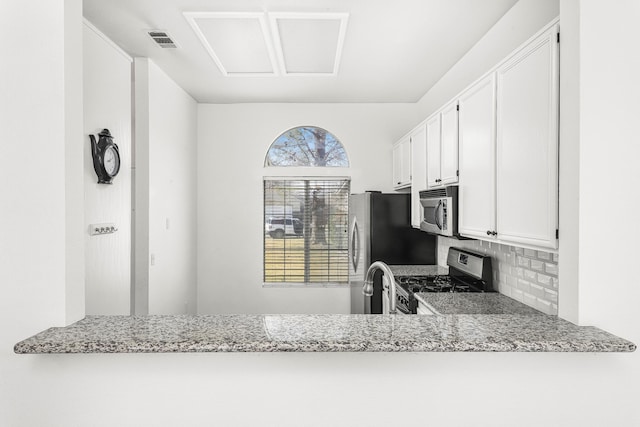 kitchen with white cabinetry, backsplash, light stone counters, and appliances with stainless steel finishes