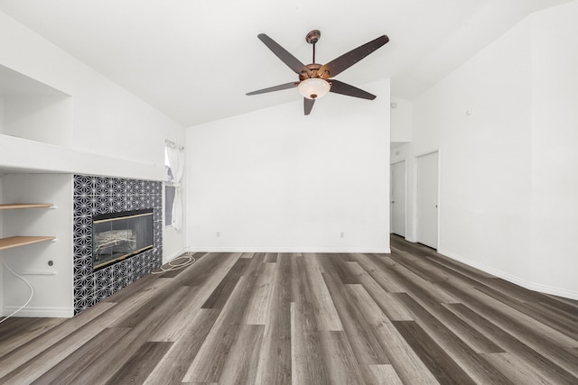 unfurnished living room with high vaulted ceiling, dark wood-type flooring, a tile fireplace, and ceiling fan