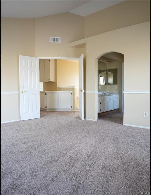 spare room featuring high vaulted ceiling, arched walkways, light carpet, baseboards, and visible vents