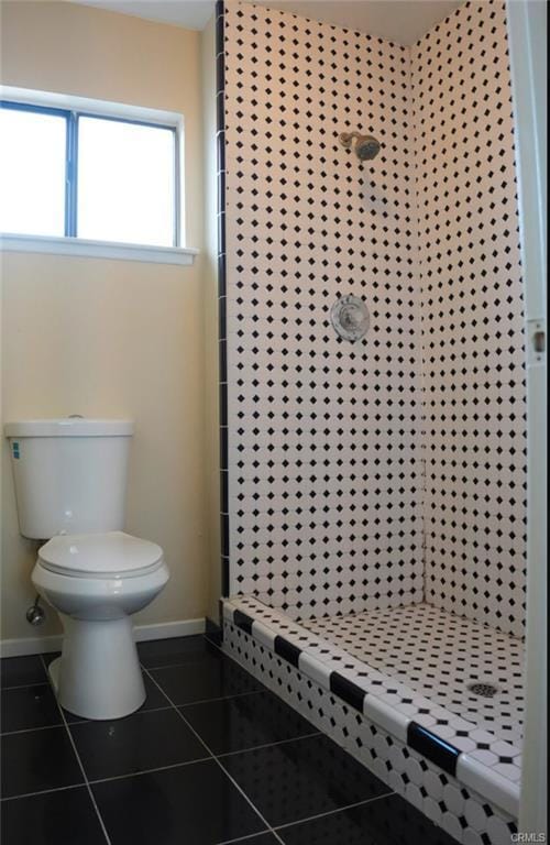 bathroom featuring tile patterned floors, baseboards, a stall shower, and toilet