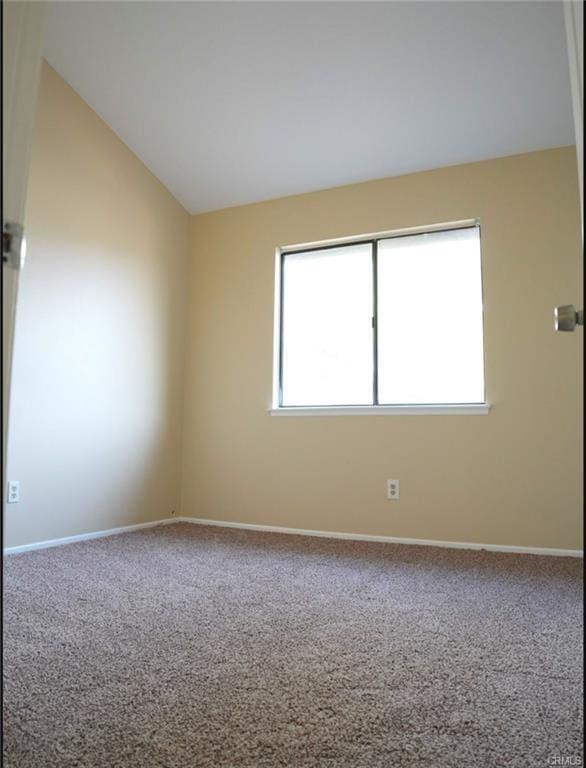 unfurnished room featuring baseboards, vaulted ceiling, and carpet
