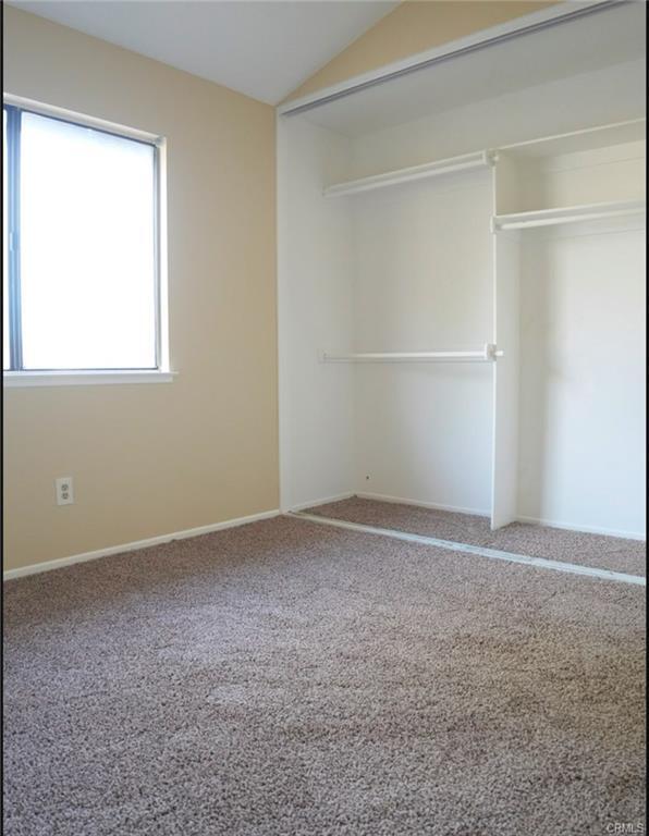 unfurnished bedroom with baseboards, vaulted ceiling, carpet flooring, and a closet