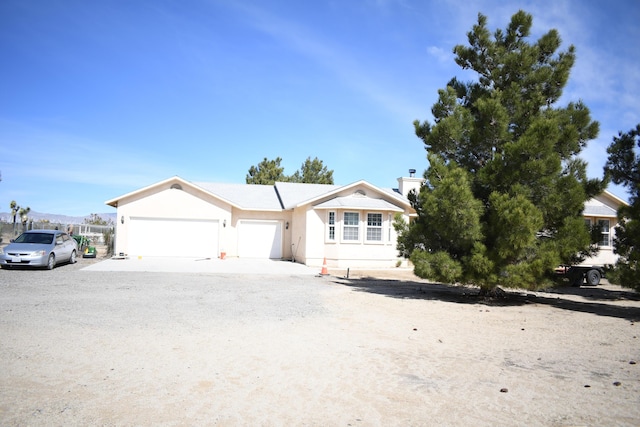 single story home with dirt driveway and an attached garage