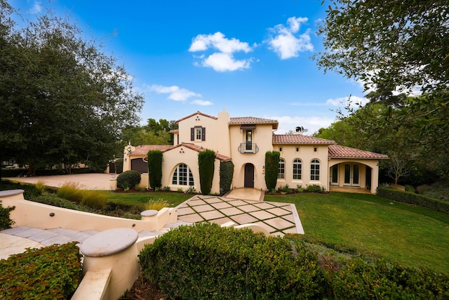 mediterranean / spanish-style home featuring a tile roof, a front yard, stucco siding, french doors, and a chimney