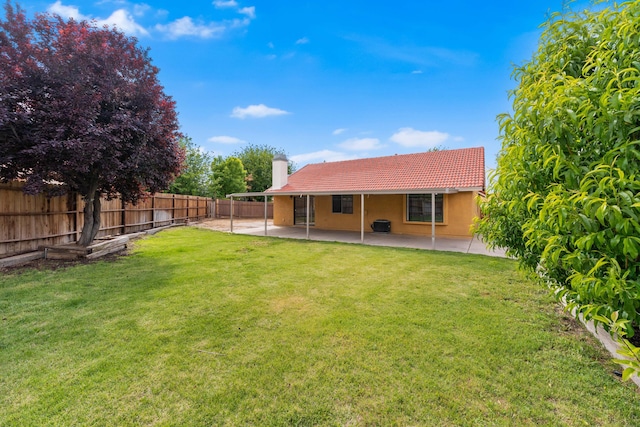 rear view of property with a fenced backyard, a chimney, a yard, and a tiled roof