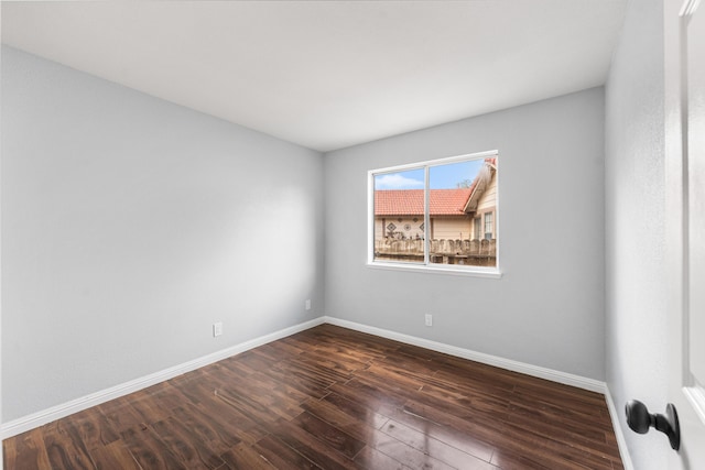 empty room featuring baseboards and dark wood-style floors