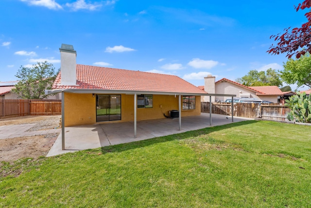 back of house with a tile roof, stucco siding, a fenced backyard, a chimney, and a yard