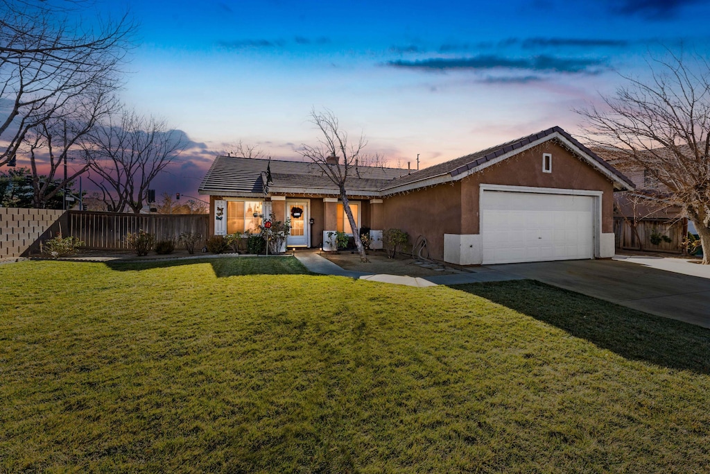 single story home featuring a lawn and a garage