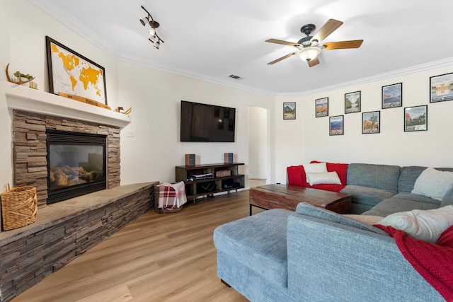 living room with crown molding, a fireplace, a ceiling fan, wood finished floors, and arched walkways