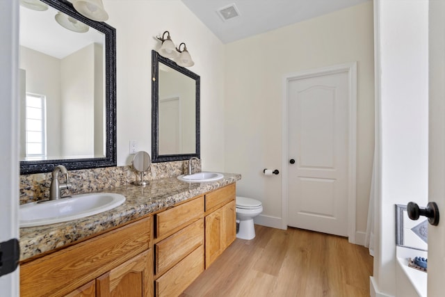 bathroom with wood finished floors, toilet, and double vanity