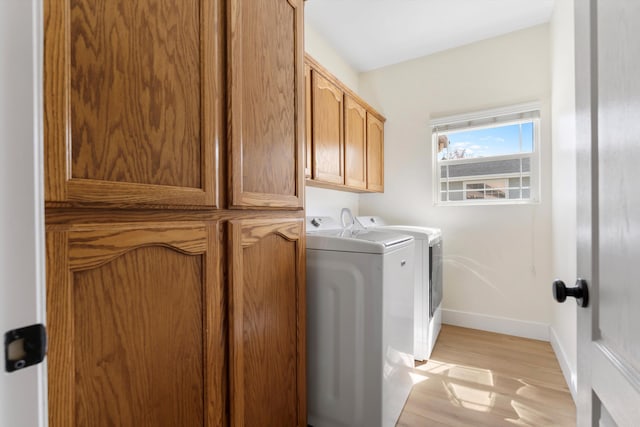 washroom with separate washer and dryer, baseboards, light wood-type flooring, and cabinet space
