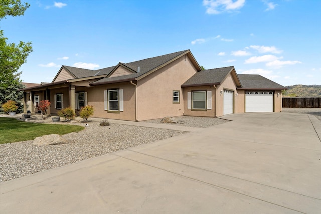 view of front facade featuring a garage, driveway, stucco siding, and fence