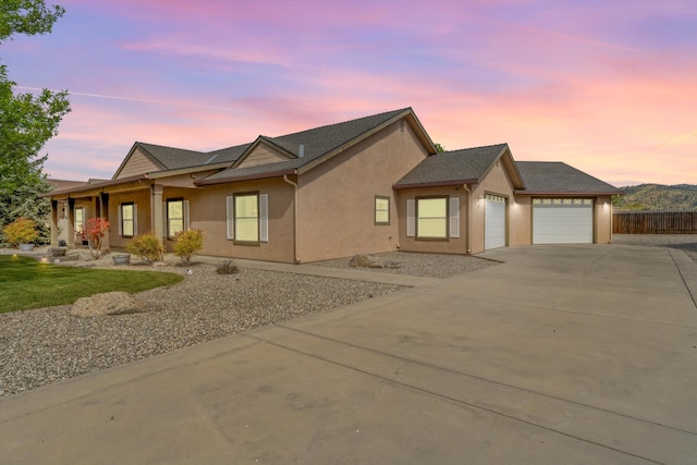 single story home with a garage, driveway, stucco siding, and fence