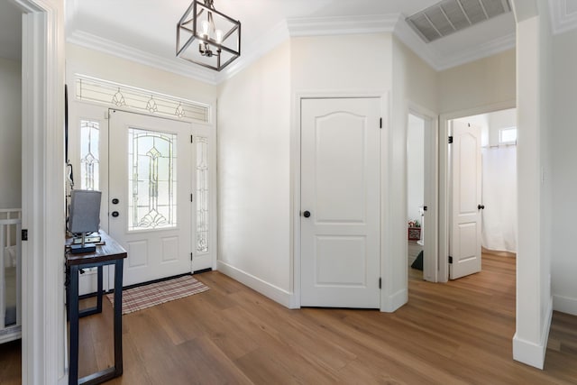 foyer entrance with wood finished floors, a chandelier, crown molding, and baseboards
