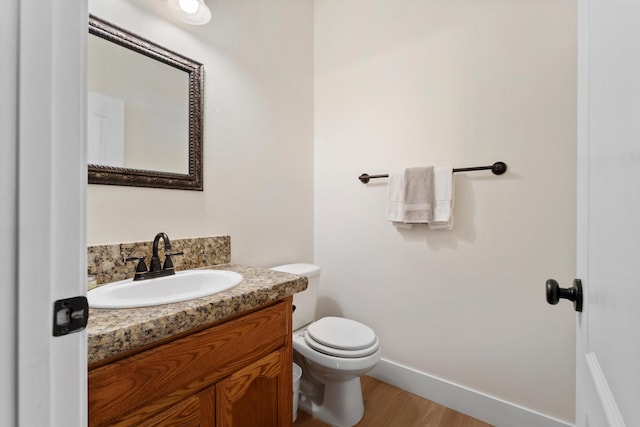 bathroom with vanity, wood finished floors, toilet, and baseboards
