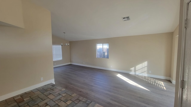 empty room featuring dark hardwood / wood-style floors, lofted ceiling, and a notable chandelier