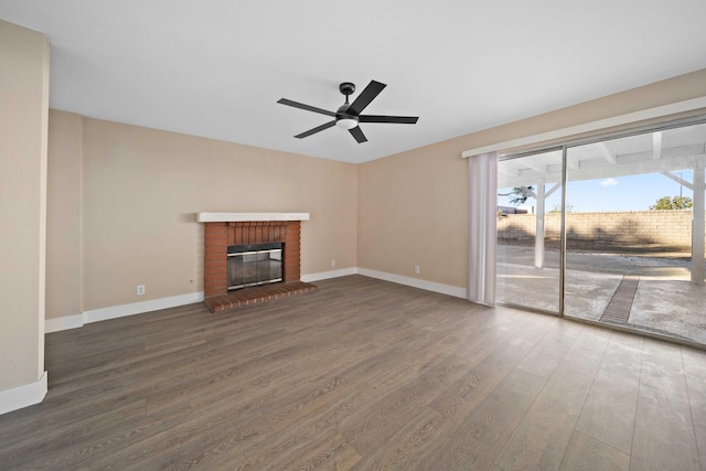 unfurnished living room featuring ceiling fan, dark hardwood / wood-style flooring, and a brick fireplace