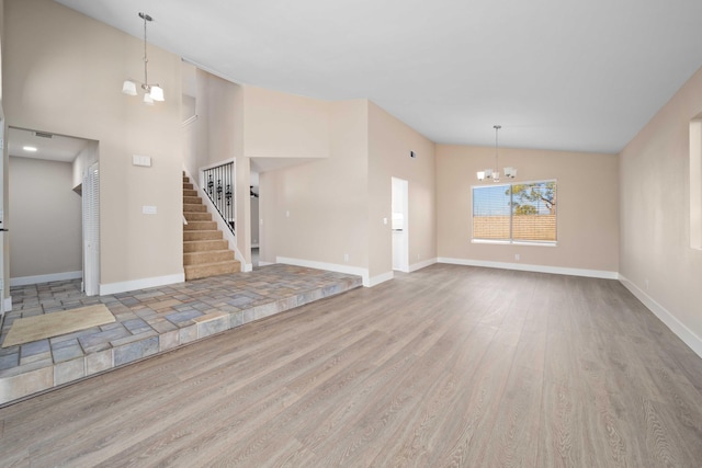 unfurnished living room with hardwood / wood-style flooring, lofted ceiling, and an inviting chandelier