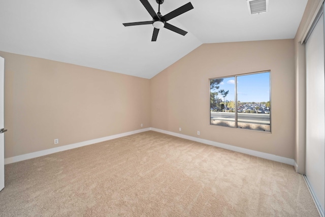 spare room with ceiling fan, light colored carpet, and vaulted ceiling