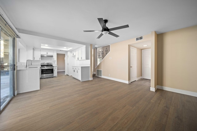 unfurnished living room featuring hardwood / wood-style floors, ceiling fan, and sink