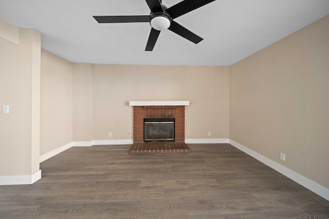 unfurnished living room with ceiling fan, a fireplace, and dark wood-type flooring