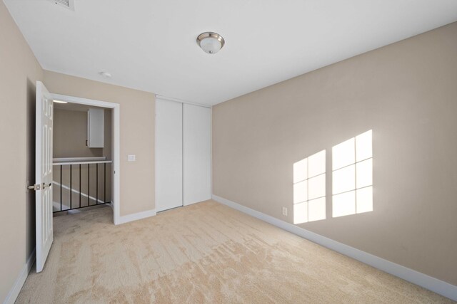 unfurnished bedroom with light carpet and a closet