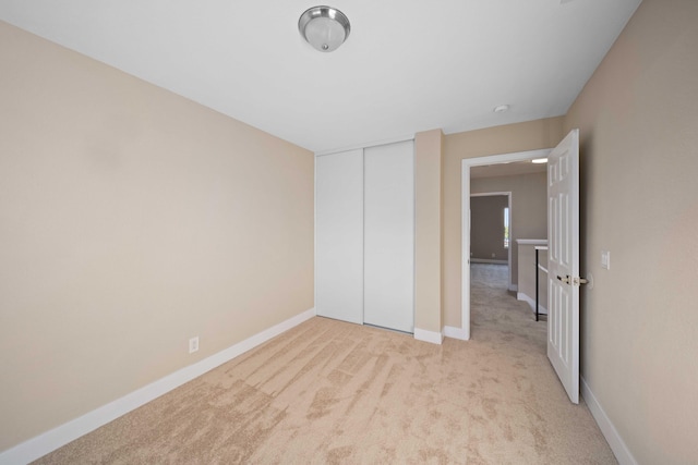 unfurnished bedroom featuring light carpet and a closet