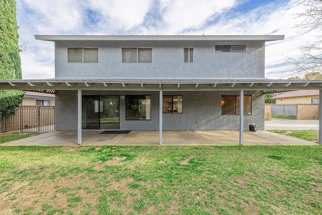 rear view of property with a patio, a yard, fence, and stucco siding