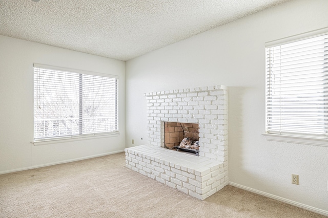 living area with a textured ceiling, carpet floors, a fireplace, and baseboards