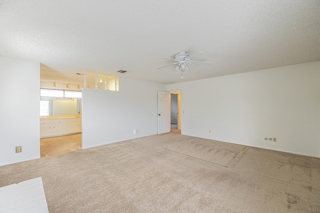 carpeted spare room with a ceiling fan, visible vents, and a textured ceiling