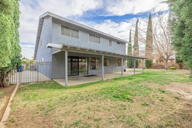 rear view of property featuring stucco siding, a patio, fence, and a lawn