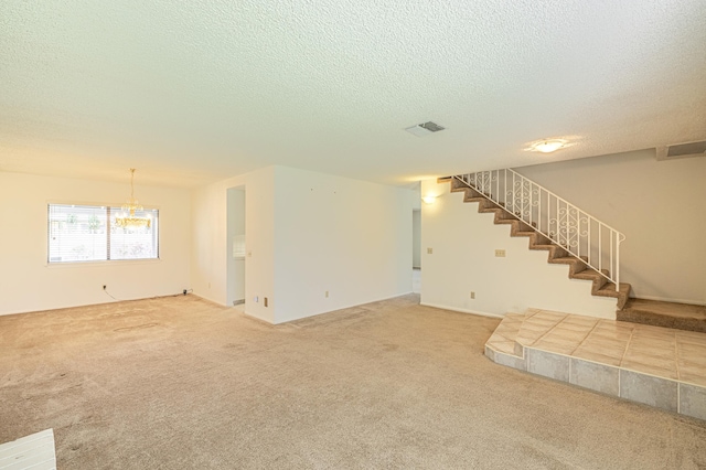 unfurnished living room with visible vents, stairway, a textured ceiling, and light colored carpet